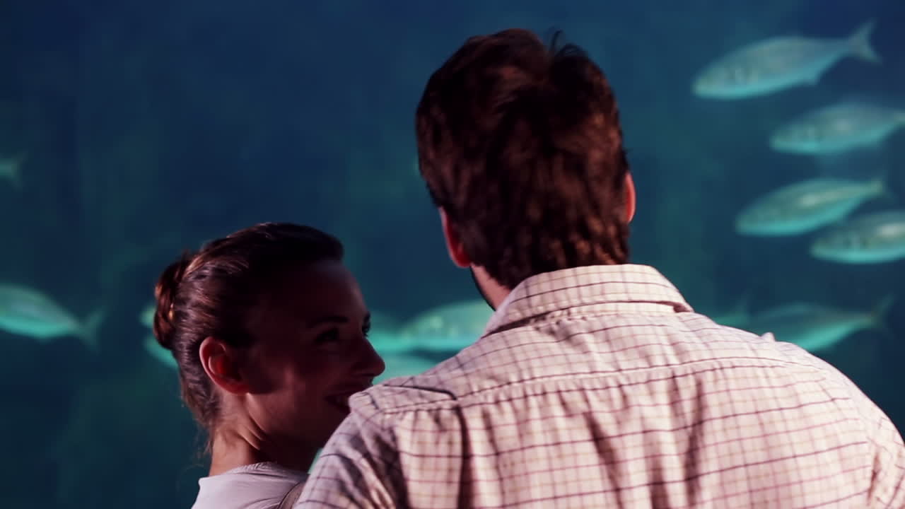 una pareja feliz tomando fotos de un tanque de peces.