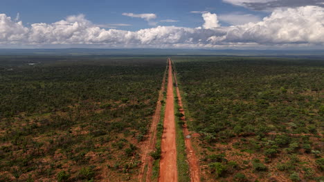 winding dirt road cutting through endless wilderness with open skies and dramatic clouds