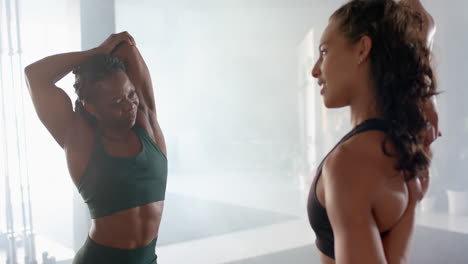 stretching and chatting, two women in gym wearing athletic wear, staying fit