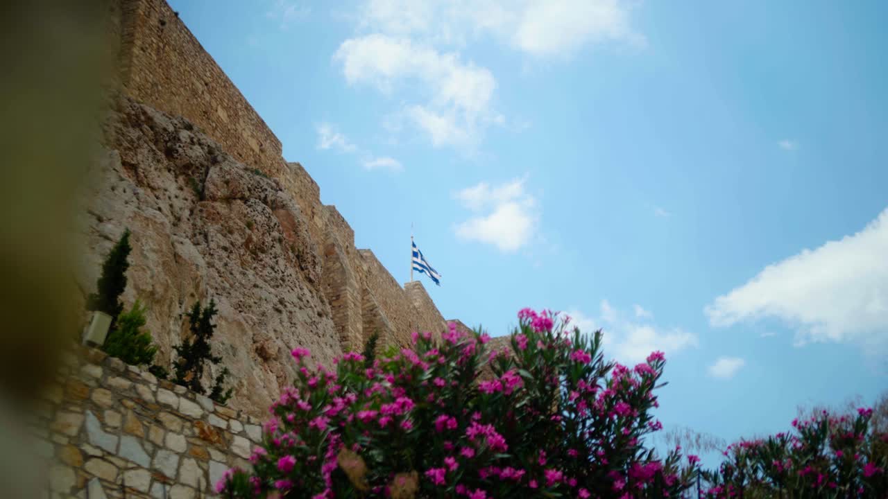 Bandiera greca che sventola al vento in cima a un'antica fortezza ad Atene