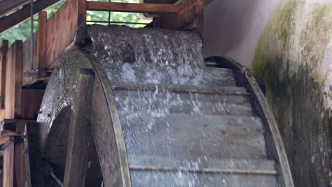 Slow-motion-close-up-of-rotating-wooden-watermill-in-mountains