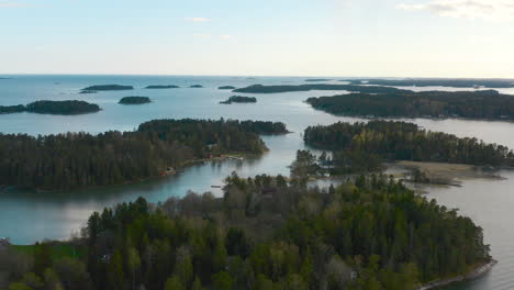 pulling to the right a drone shows the view from flying very high above the island forests found in scandinavia.