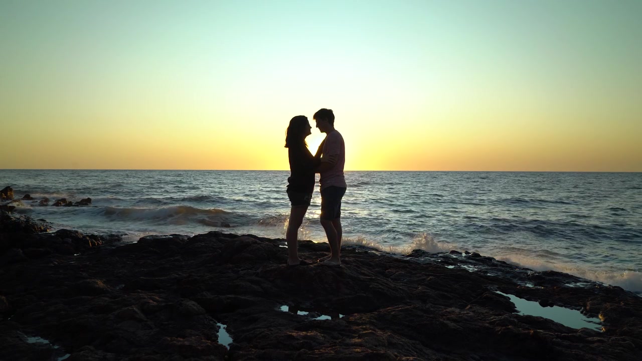Silhouette di coppia che si bacia sugli scogli in spiaggia