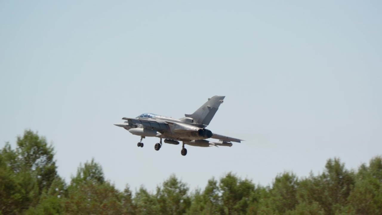Fighter jet approaching over treetops to land