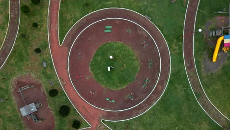 boom up aerial from the top of a wheel with various exercise equipment in a small plaza in a remote mexican town