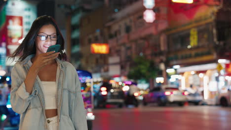 woman using phone in a vibrant asian city street at night