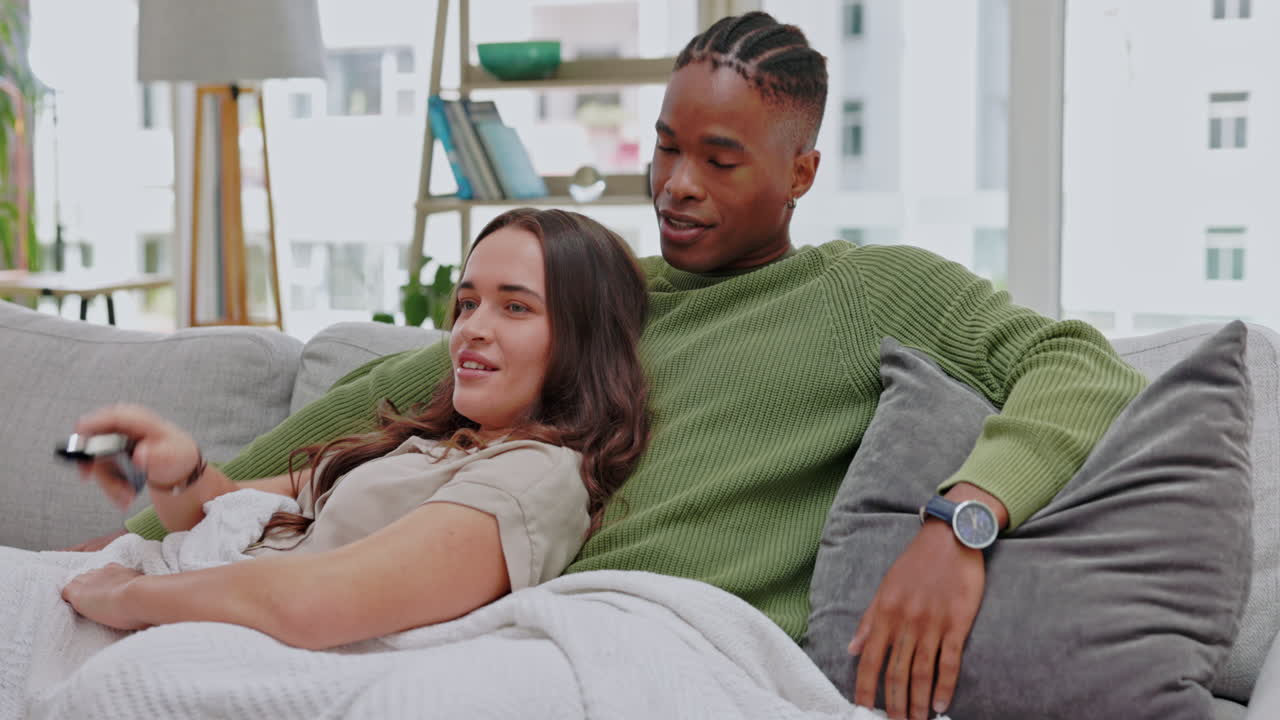 viendo televisión, hablando una pareja interracial