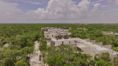 Tulum-Mexico-Aerial-v9-low-drone-flyover-newly-developed-upscale-neighborhood,-luxury-homes,-building-complex-with-rooftop-pools-surrounded-by-lush-greenery---Shot-with-Mavic-3-Pro-Cine---July-2023