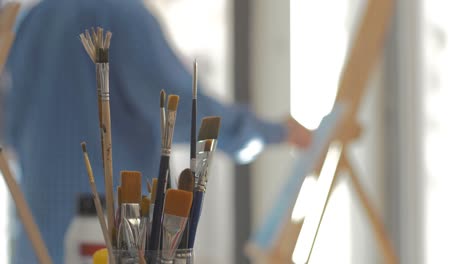 Artist-painting-in-art-studio-Brushes-in-focus