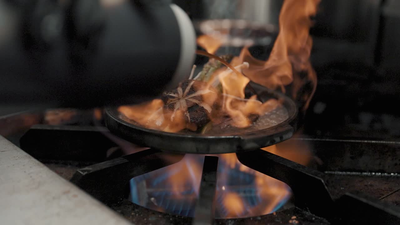 Juicy mushroom steak and asparagus sizzles on a hot plate above an open flame