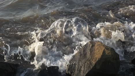 olas del mar a cámara lenta rompiendo en las rocas de la playa
