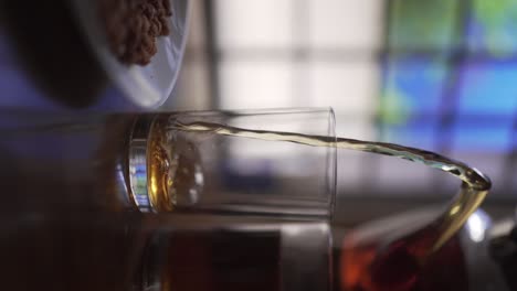 pouring hot black coffee into glass and peanuts served in plate | vertical video | close-up shot