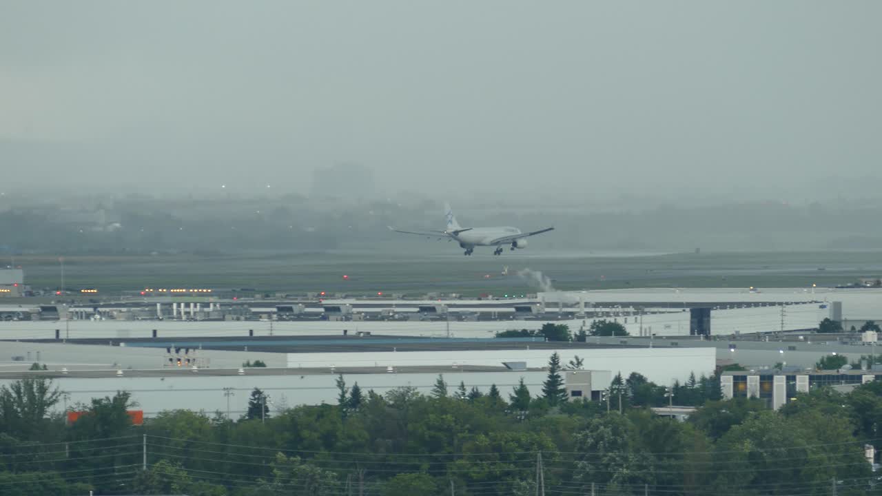Wide shot of airplane landing on runway of the Airport during dark clouds and thunderstorm.Toronto,Canada.