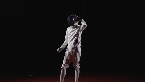 a young woman fencer in a white uniform and mask, holding a sword, with a determined expression on her face. the black background makes her stand out and draws attention to her athleticism and focus.