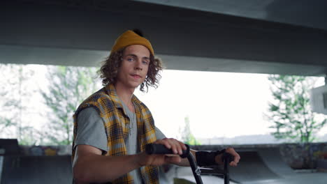 Stylish-man-relaxing-training-at-skate-park.-Teen-gesturing-hand-at-skatepark.