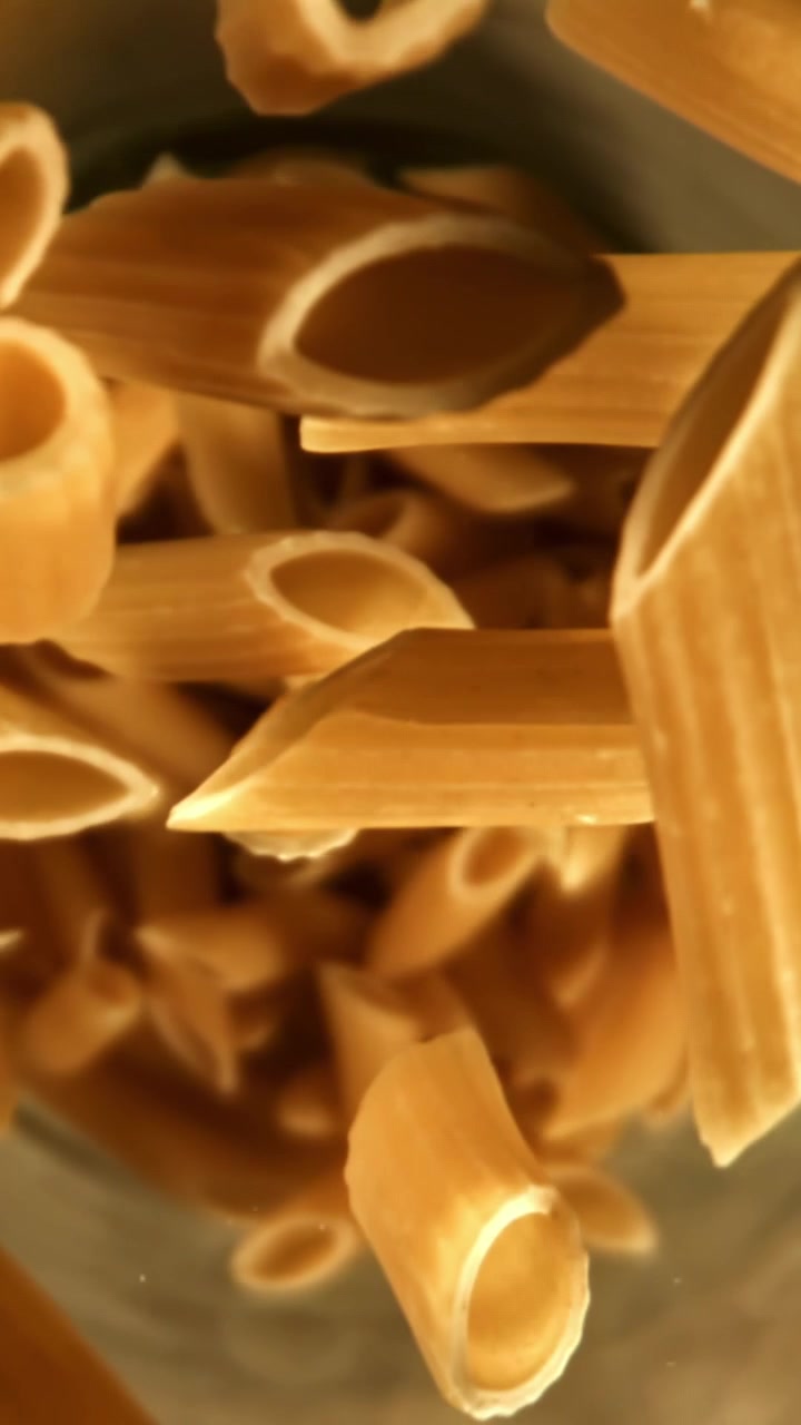 Penne crude che cadono in un contenitore
