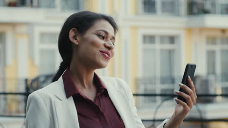 mixed race businesswoman having video chat outdoors. smiling woman talking phone