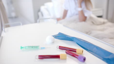 Syringe-and-blood-samples-on-table,-and-defocused-patient-in-hospital-bed,-slow-motion