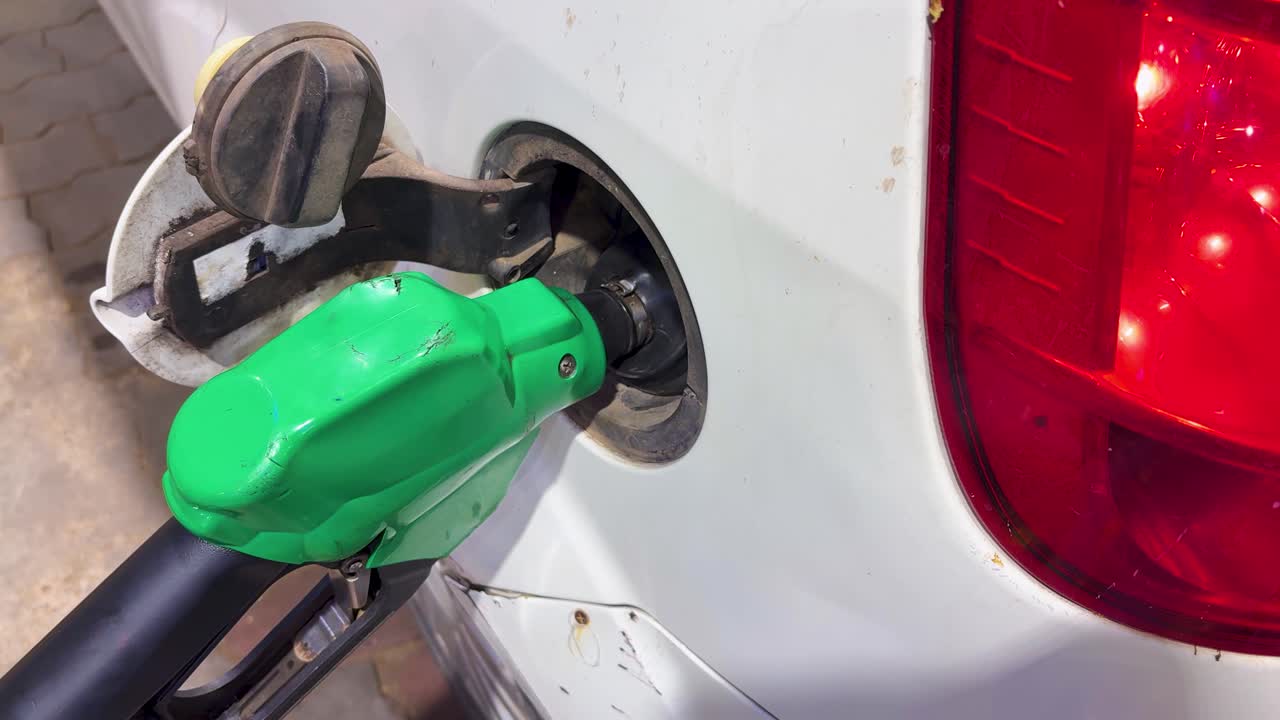 Primo piano di ugello del carburante che rifornisce l'auto alla stazione di servizio.