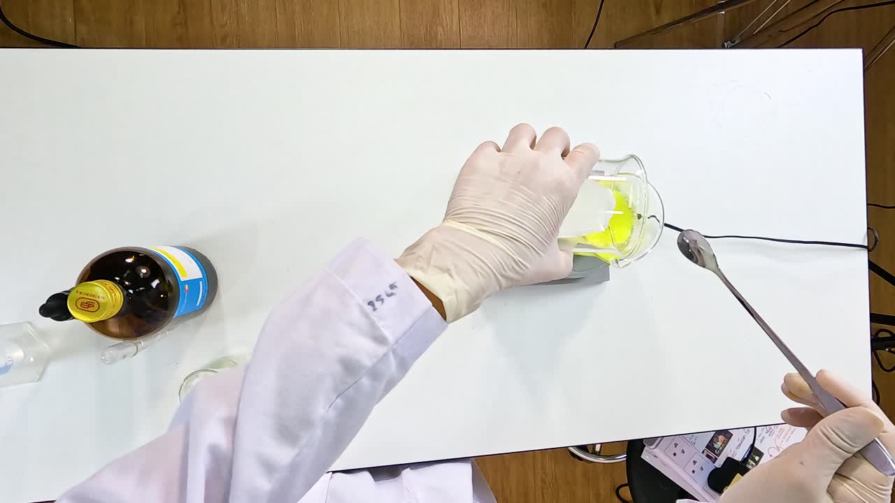 A scientist conducts an iodine clock reaction experiment, mixing chemicals in a lab setting with precise equipment and controlled lighting