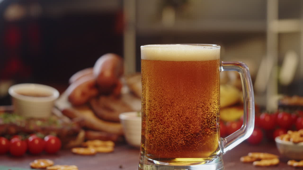 Birra dorata che si versa in un boccale su un tavolo con stuzzichini