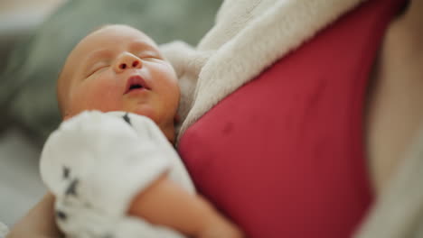 yawning newborn baby in mother's arms