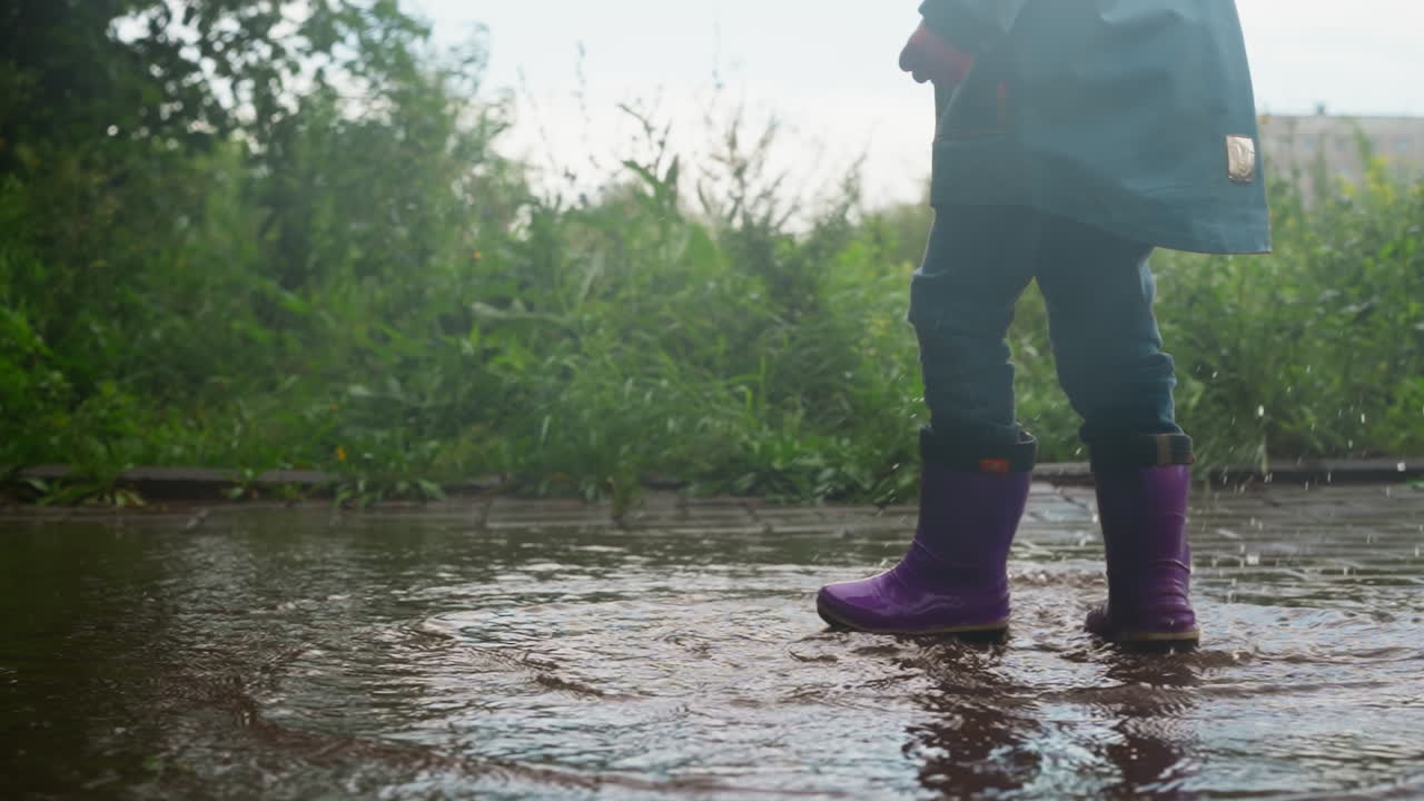 A little girl jumps in a puddle and splashes water