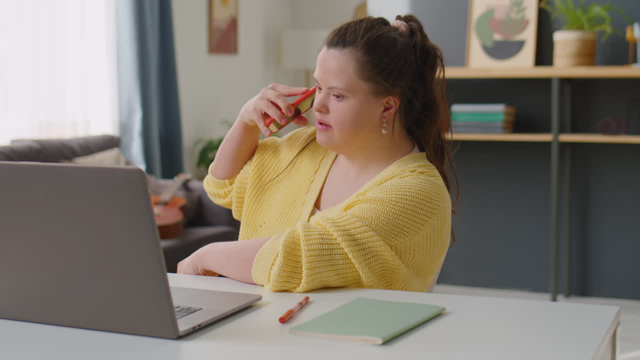 Woman with Down Syndrome Talking on Phone while Working Remotely