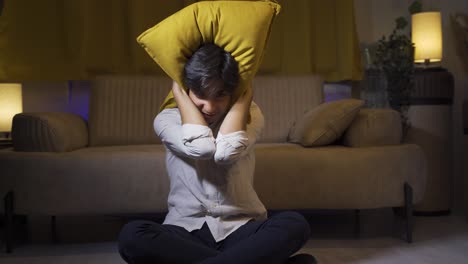 the man who presses the pillows on his head with fear.