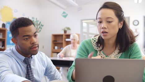 Teacher and student using laptop at an adult education class