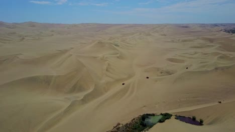 camiones de arena conduciendo sobre dunas de arena en el oasis de huacachina con un disparo aéreo de drone