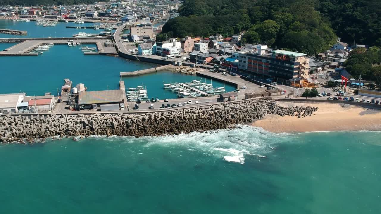 Drone avanza e scende verso la spiaggia, il porto turistico e la città costiera di Wakayama