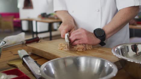 Caucasian-male-chef-kutting-meat-on-a-kitchen-table