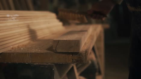 the man brushes away the shavings and wood dust from the rail. checks the surface of the wood on the roughness. extremely close up. workshop