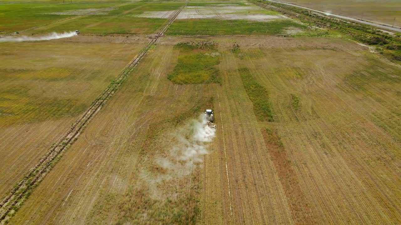 Tratores roçando ervas daninhas em um campo verde - imagem aérea de drone