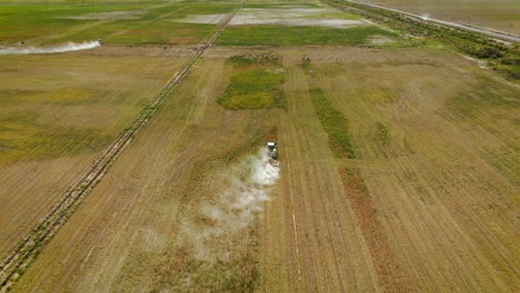 tractors mowing weeds on a green field - aerial drone shot