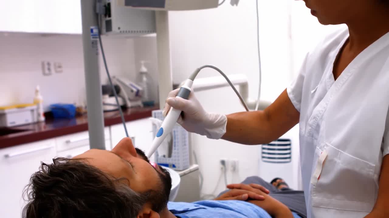 Dentista che esamina un paziente maschio con strumenti