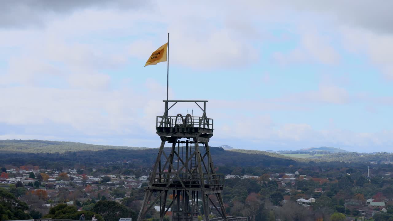una bandera ondea en la cima de una torre contra un cielo nublado en melbourne, australia la escena captura una vista panorámica de la ciudad