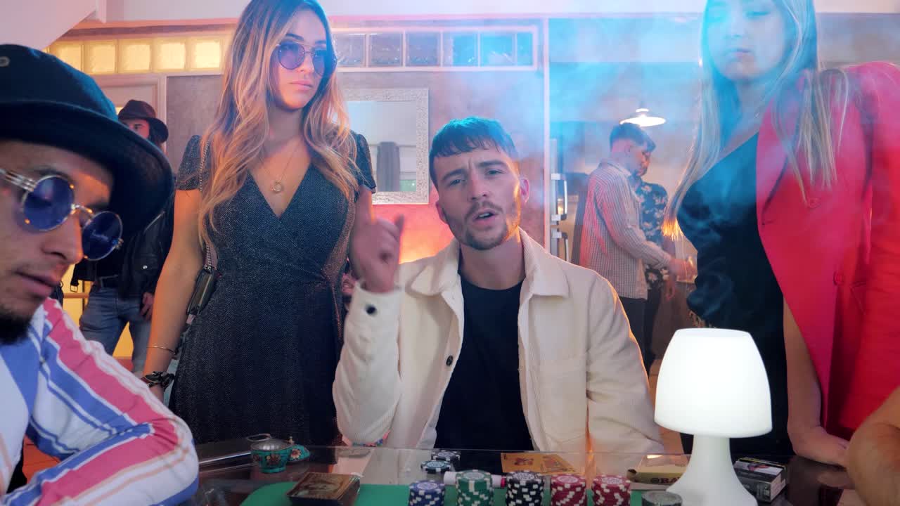 slow motion shot of a musician singing whilst playing poker and smoking at a party