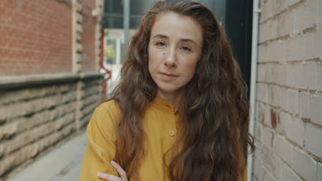 woman in a yellow shirt, smiling, in a city alley