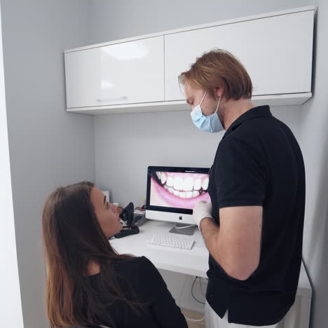 stomatologist giving consultation to a woman. doctor shows young patient the situation of her teeth. dentist shows photo of woman's teeth on the screen in dental office.