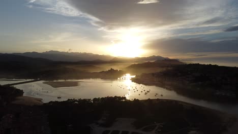 La-Increíble-Ciudad-De-San-Vicente-De-La-Barquera-En-Cantabria-En-El-Norte-De-España-Frente-A-Una-Impresionante-Puesta-De-Sol-Con-Niebla-Y-Nubes,-Drone