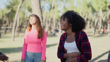 a diverse group of friends smiling and talking in a sunny park