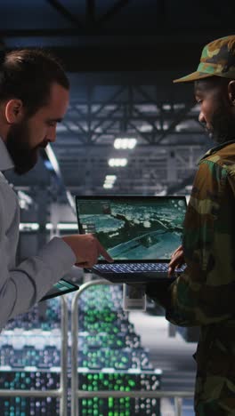 vertical video military server hub technician reviewing tactical dashboard on laptop