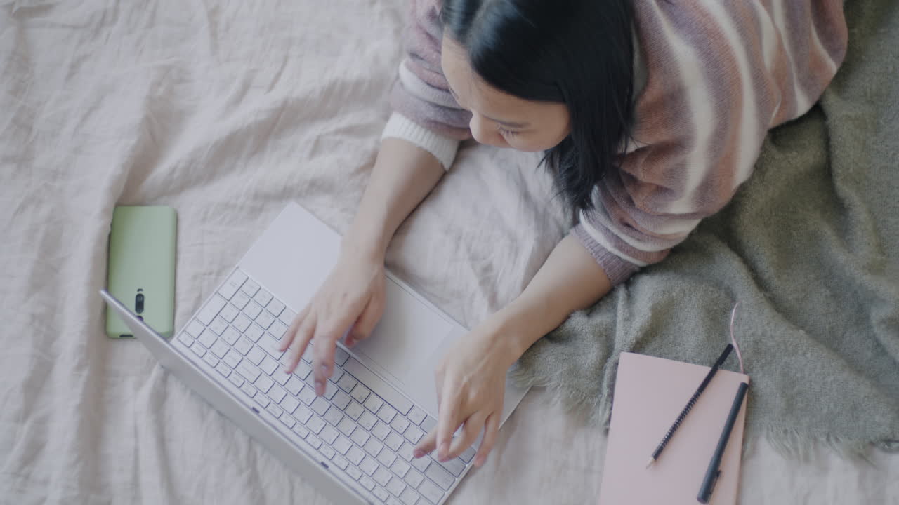 침대에 노트북으로 일하는 여자