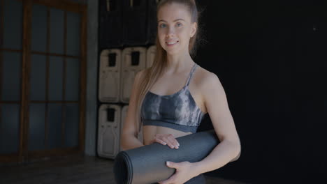 woman holding yoga mat in studio