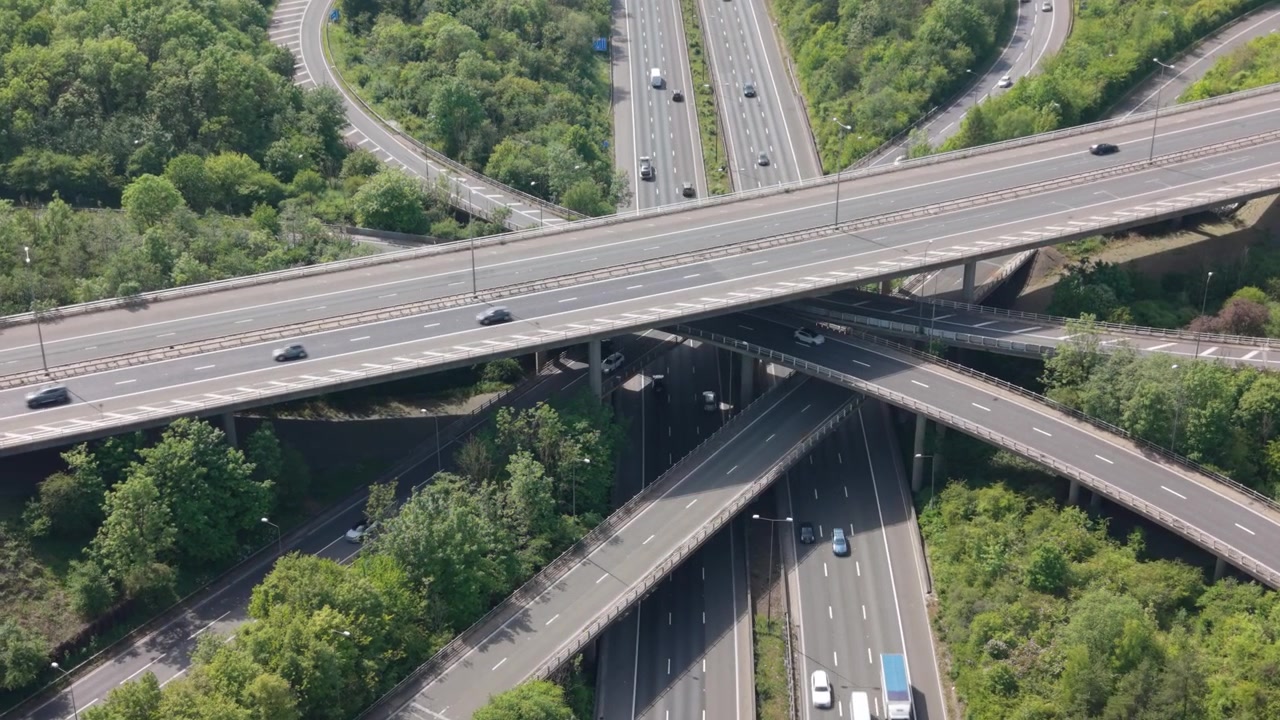 Una perspectiva aérea muestra un gran y concurrido intercambio de autopistas de varios niveles con muchos coches y camiones circulando por las carreteras.