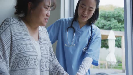 smiling asian female doctor helping happy female patient walk with walking frame at hospital