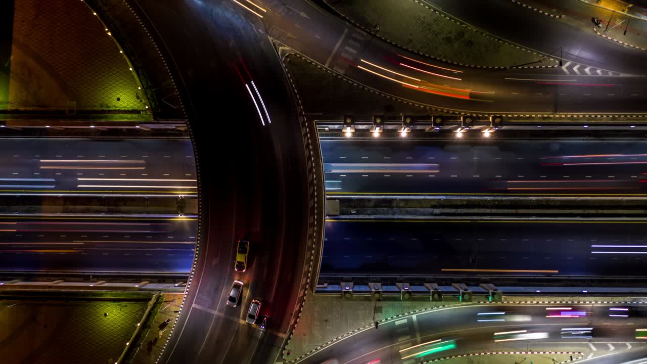 4k time lapse vista aérea de la intersección de la rotonda de la carretera en la ciudad por la noche con movimiento ligero de vehículos.