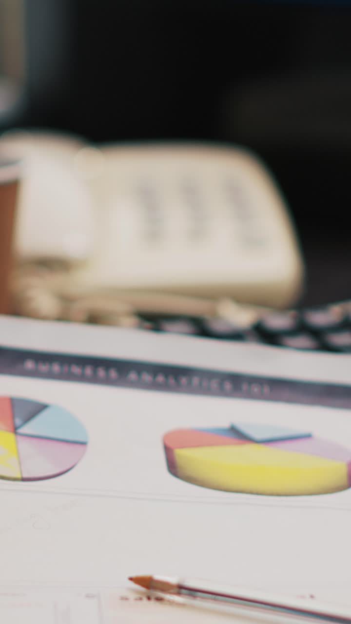 Vertical video Bookkeeping documents containing business analytics next to coffee cup, close up